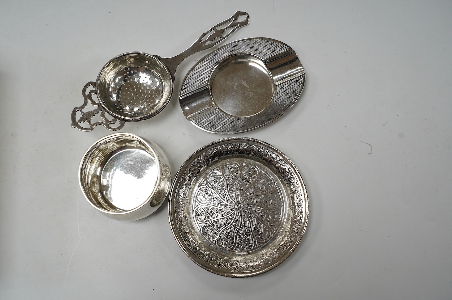 Sundry small silver and white metal items including silver tea strainer on stand and ashtray, pierced silver bowl, sterling dishes and dwarf candlesticks, etc. Condition - poor to fair